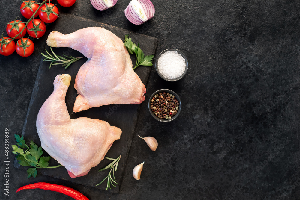 two raw chicken legs with spices and herbs on a stone background with copy space for your text two raw chicken legs with spices and herbs on a stone background with copy space for your text
