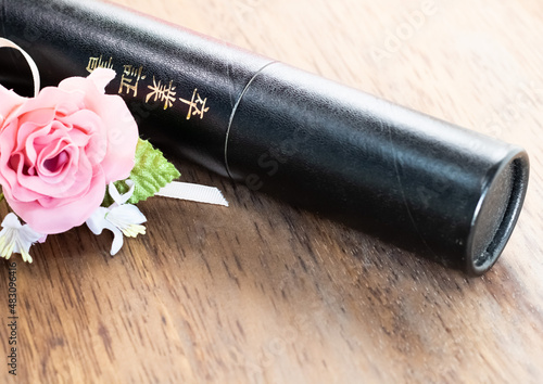 卒業証書の入っている筒とバラのコサージュ