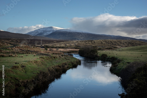 A river at the edge of Wild Nephin National Park in Ireland. Snow on the mountaintops of Wild Nephin Mountains. 