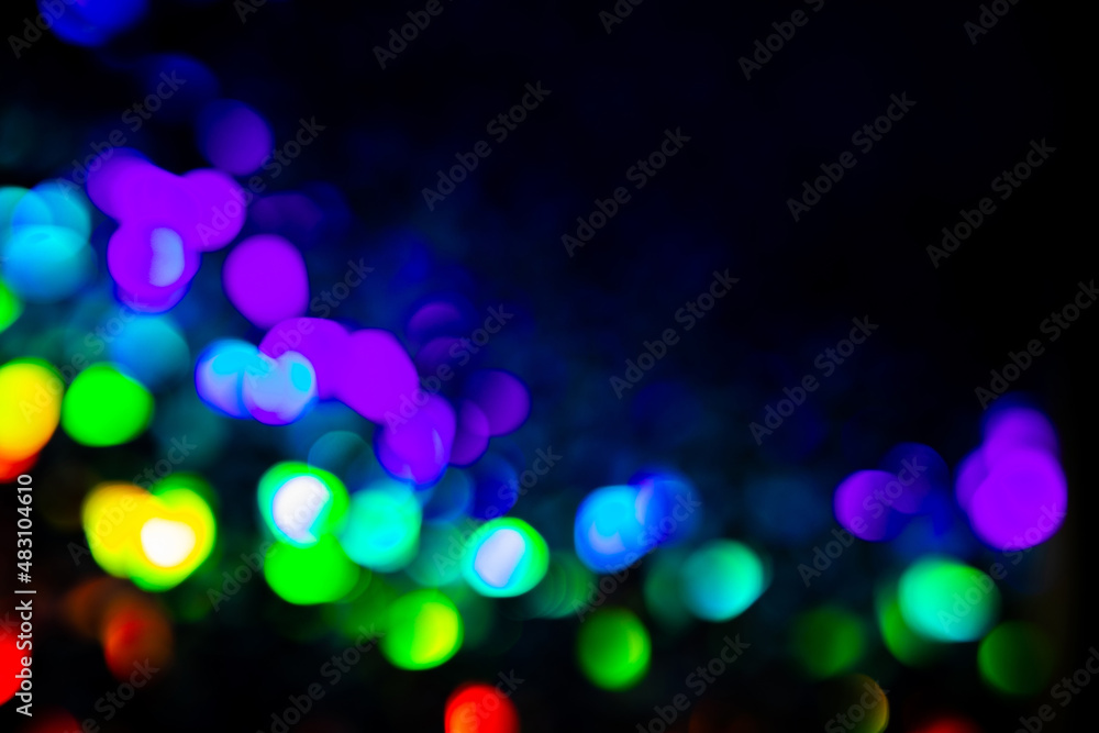 Trendy purple, green, pink circles bokeh festive glitter dark background with copy space. Christmas lights bokeh overlay pattern. Modern unicorn color abstract design