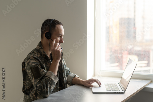 Soldier working with laptop in headquarters building photo