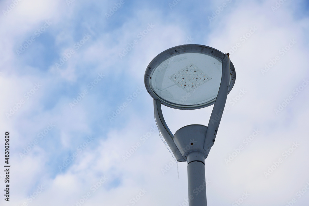 Led lamp with icicles on winter sky background. Electric lighting in park, energy-saving street lantern