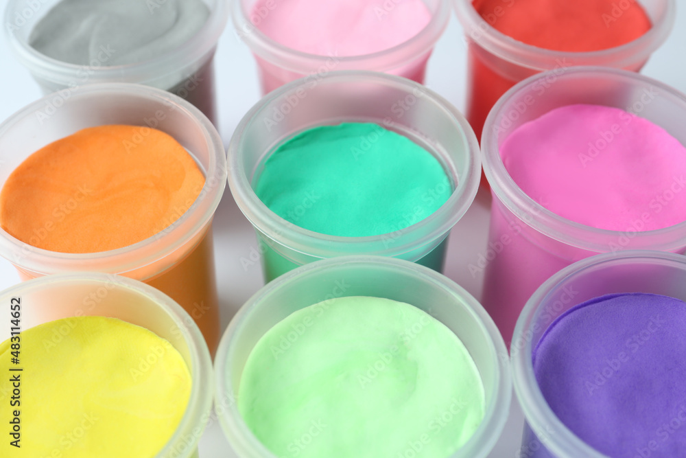 Plastic containers with colorful play dough on white background, closeup Plastic containers with colorful play dough on white background, closeup