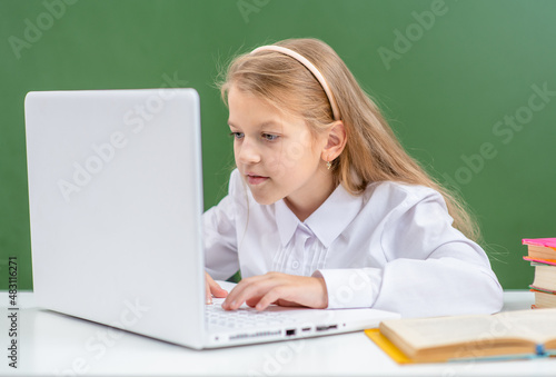 Happy young girl studies with laptop in a school