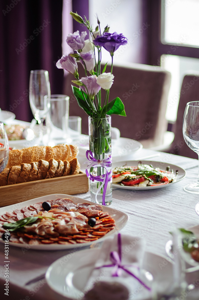 Сatering table with food, flowers and glass stemware at restaurant before party 