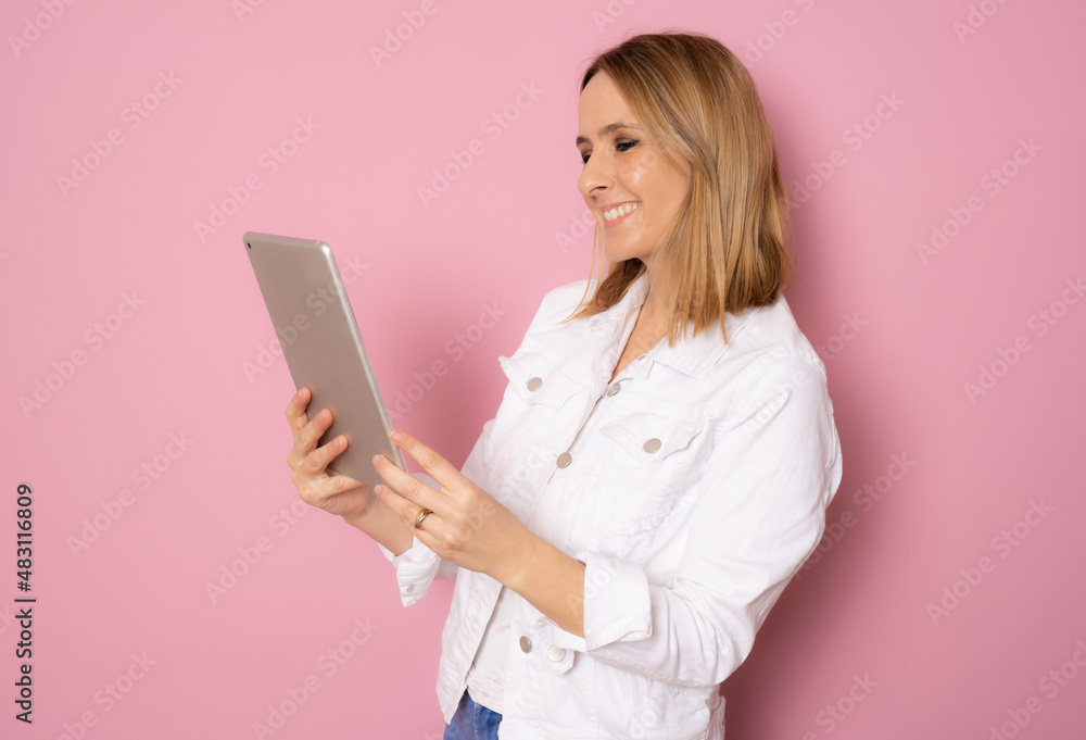 Portrait of happy young blonde woman in casual clothes using tablet isolated over pink background. Portrait of happy young blonde woman in casual clothes using tablet isolated over pink background.