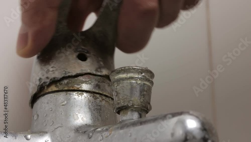 Close-up of a man's hand turning the broken lever of a water faucet photo