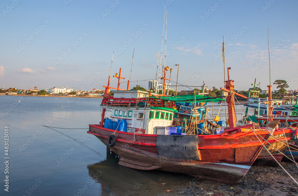 In the evening, colorful fishing boats are securely tied down directly at the pier with seaman's ropes and knots