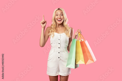Smiling woman pointing up holding shopping bags at studio