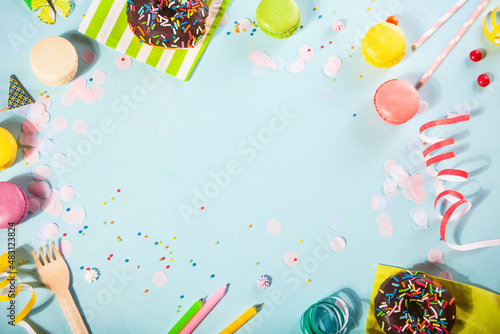 Party frame. Birthday candles, donuts, sweets, candies on the blue background. Top view. Copy space.