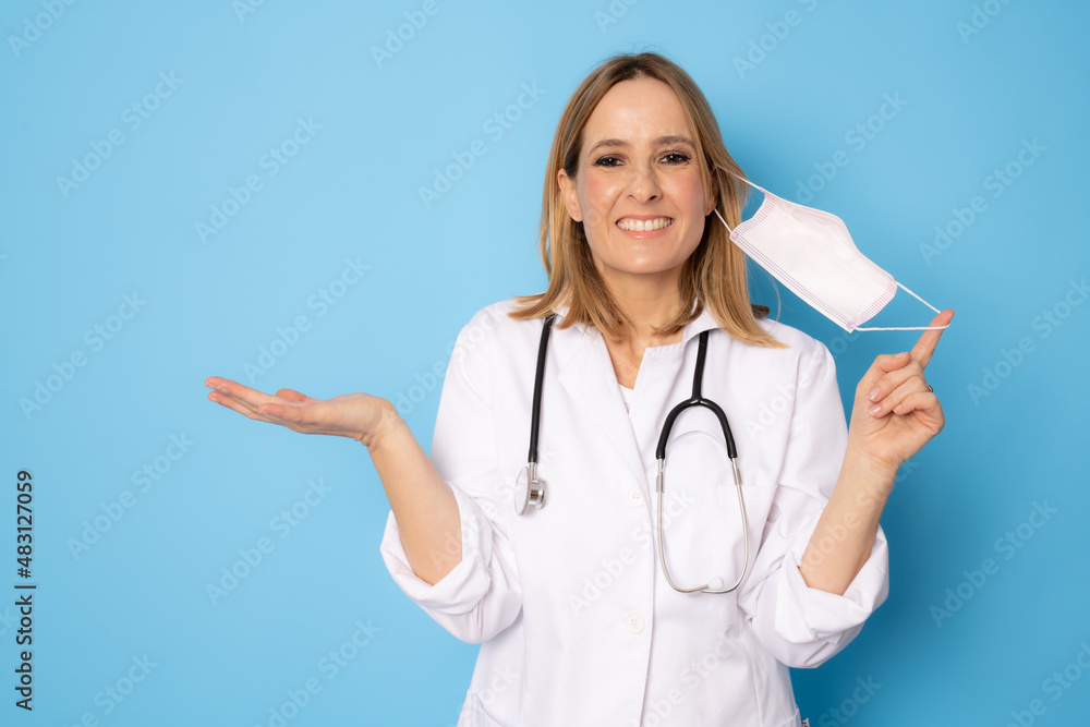 Confident young woman doctor wearing surgical mask isolated on blue background. Confident young woman doctor wearing surgical mask isolated on blue background.