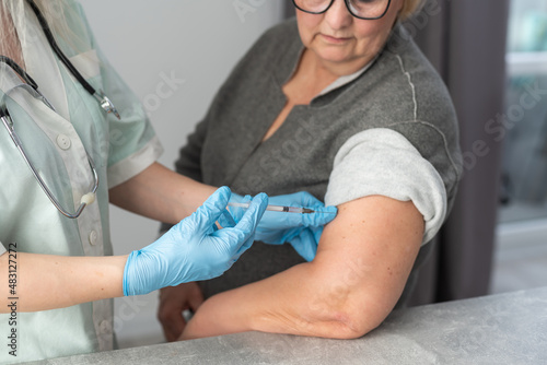 Doctor giving a senior woman a vaccination. Virus protection. COVID-2019.