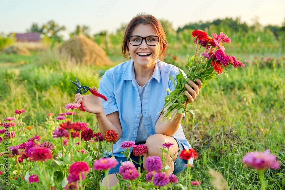 Smiling middle aged female holding bouquet of fresh zinnia flowers in garden Smiling middle aged female holding bouquet of fresh zinnia flowers in garden