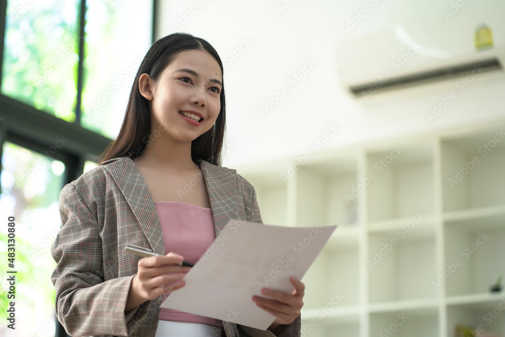 Asian woman smiling and looking forward, have a business chart in hand. Asian woman smiling and looking forward, have a business chart in hand.