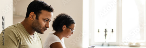 Middle eastern man and woman reading book and working with laptop