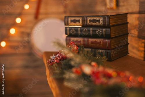 a stack of old vintage books on the fireplace with festive christmas holidays decor at home with cozy evening lighting photo