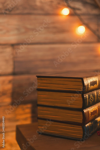 a stack of old vintage books on the fireplace or table at home with cozy evening lighting. 