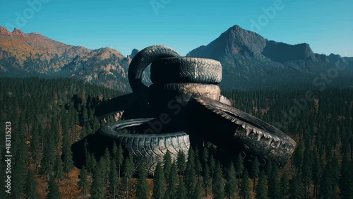 concept of environmental pollution with big old tires in mountain forest photo