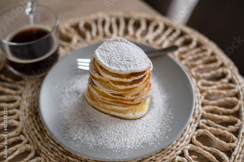 Stack of pancakes with sugar powder and cup of coffee. Close up. Breakfast concept. Home made pancakes.