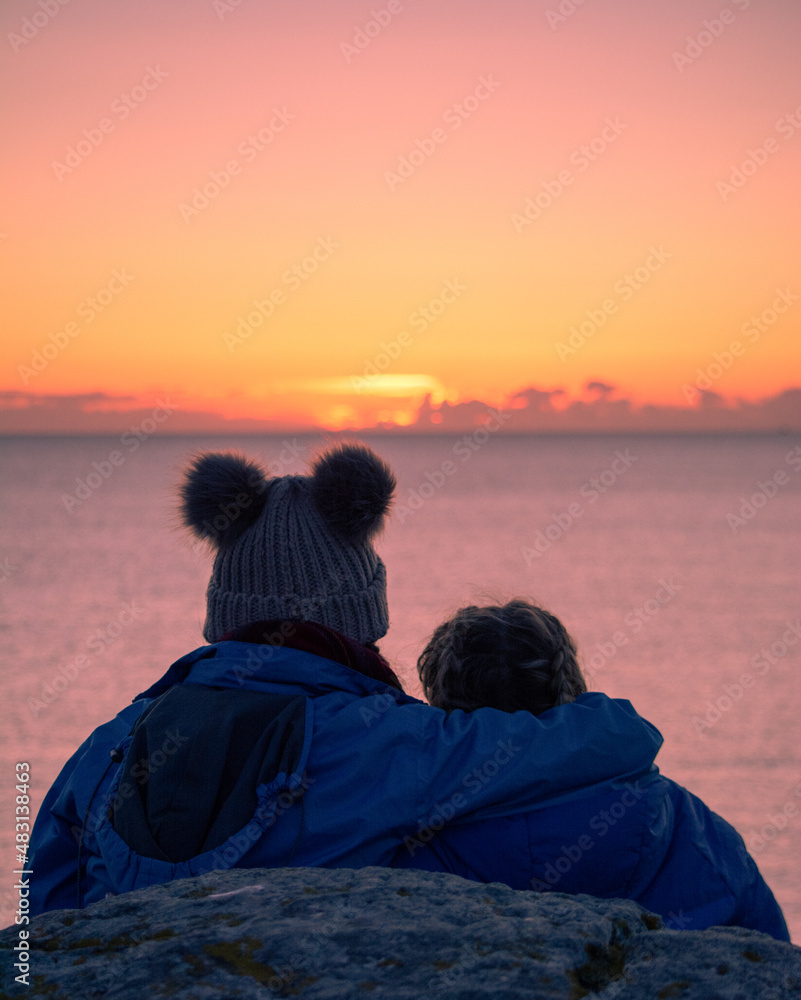 Two female friends enjoy the sunset together near Achmelvich beach, highlands, west coast, Scotland.