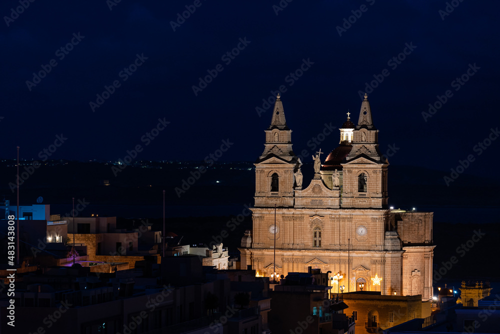 Mellieha, Malta - 01 07 2022: The cathedral twin towers and the valley by night, high angle view
