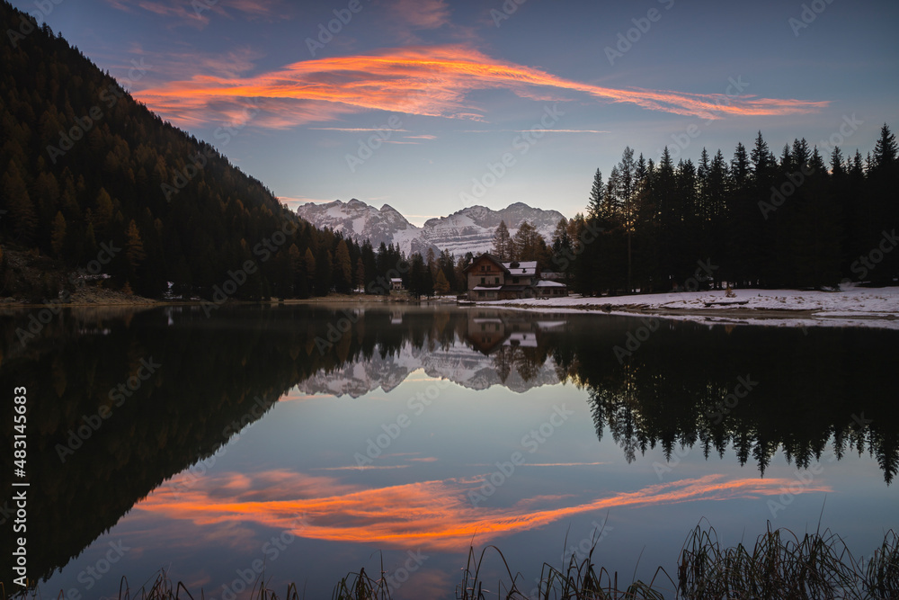 Sky at sunrise reflected in the lake Nambino, Madonna Di Campiglio, Trentino, Italy.
