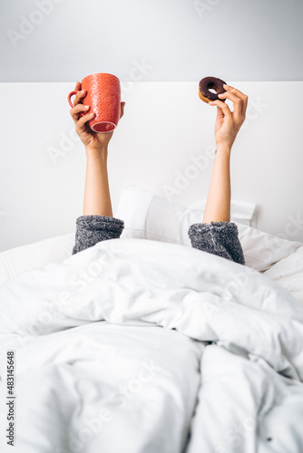 Foto Woman's hands holding a cup of coffee and a homemade donut in the morning upon w