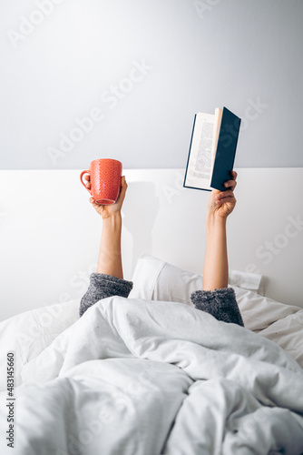 Quadro su tela Woman's hands holding a cup of coffee and a book in the morning upon waking up