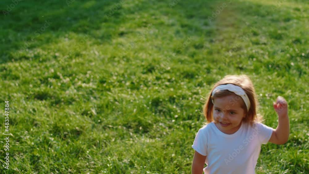 Very charismatic little girl in front of the camera with a happy face playing on the grass in the middle of the park Very charismatic little girl in front of the camera with a happy face playing on the grass in the middle of the park