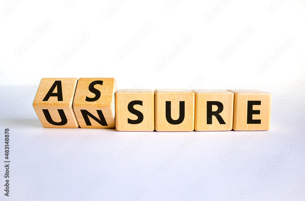 Assure or unsure symbol. Turned wooden cubes and changed the concept word unsure to assure. Beautiful white table, white background, copy space. Business and assure or unsure concept. Assure or unsure symbol. Turned wooden cubes and changed the concept word unsure to assure. Beautiful white table, white background, copy space. Business and assure or unsure concept.