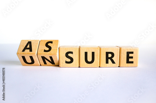Assure or unsure symbol. Turned wooden cubes and changed the concept word unsure to assure. Beautiful white table, white background, copy space. Business and assure or unsure concept. photo