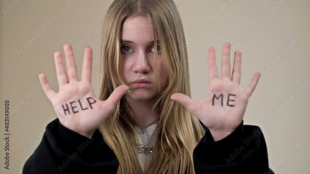 Portrait of a frustrated teenage girl showing her palms with the inscription HELP ME. Portrait of a frustrated teenage girl showing her palms with the inscription HELP ME.