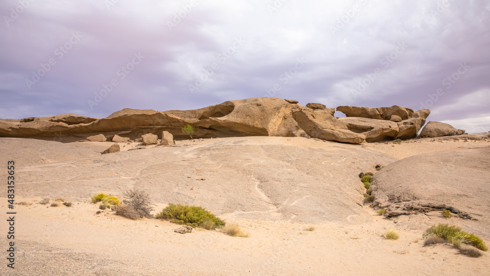 Rock formations in a totally flat sandy landscape in the Erongo region, Namibia.