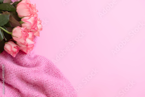 Gentle, romantic, feminine background with beautiful roses bouquet and knitted blanket on pastel pink background