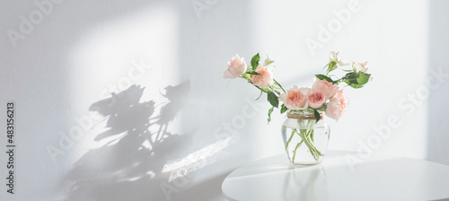 Canvas pink roses in glass jar on white modern table on background white wall