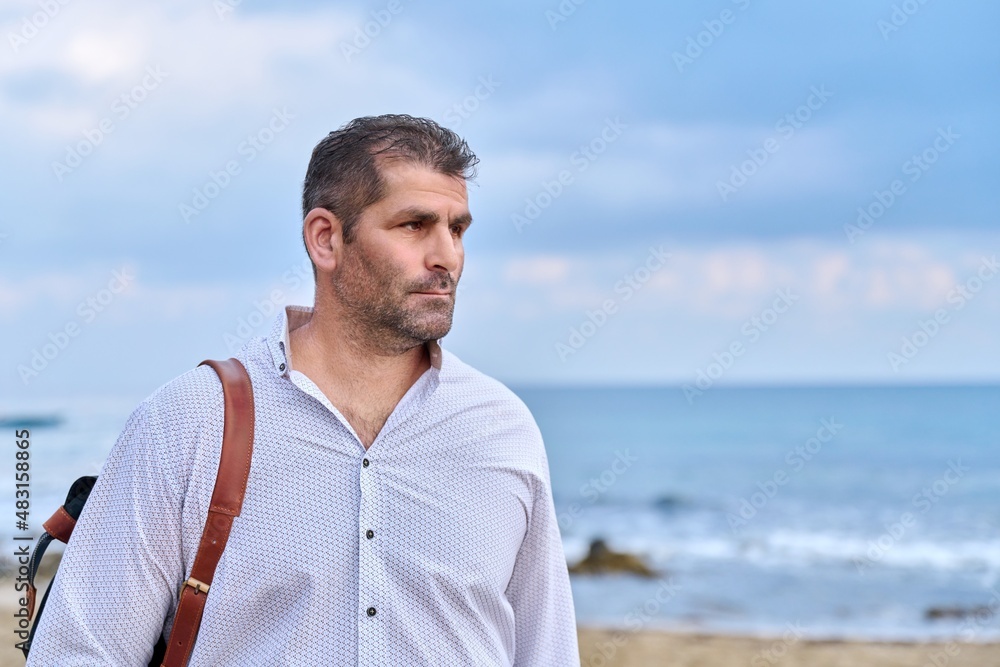 Outdoor portrait of mature man with backpack on seashore, copy space Outdoor portrait of mature man with backpack on seashore, copy space