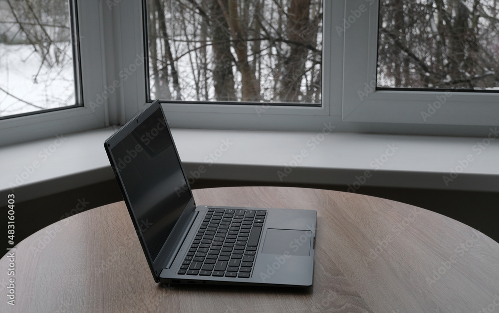 Open laptop on the table by the window Open laptop on the table by the window