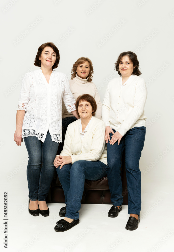 a cute grandmother sits on an armchair with her daughters and has fun on a white background.grandmother with her daughters. pensioner with women on white background a cute grandmother sits on an armchair with her daughters and has fun on a white background.grandmother with her daughters. pensioner with women on white background
