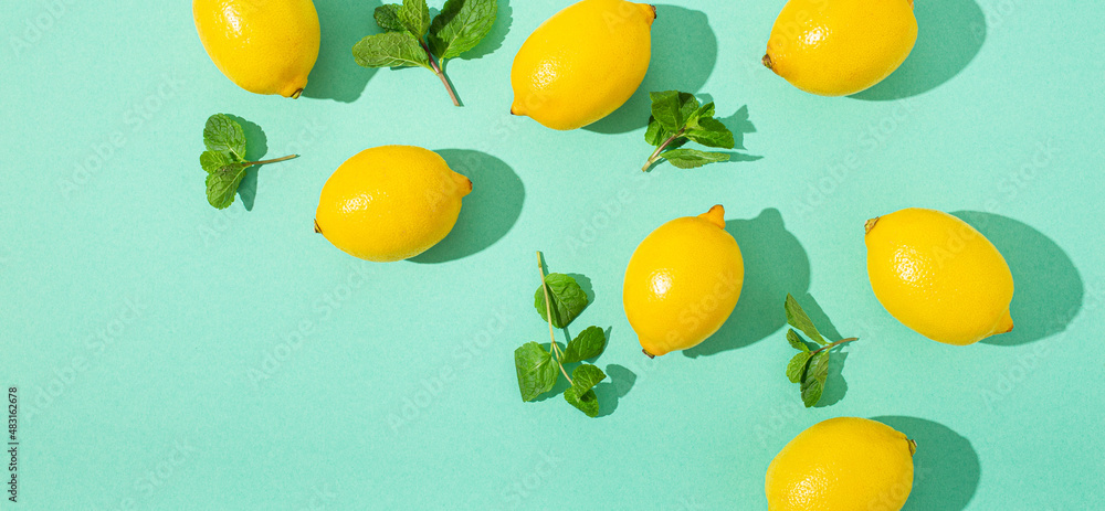 Fresh yellow lemons with mint on minimal blue background on bright sun light with hard shadows pattern summer background flat lay from above, citrus food composition, space for text Fresh yellow lemons with mint on minimal blue background on bright sun light with hard shadows pattern summer background flat lay from above, citrus food composition, space for text