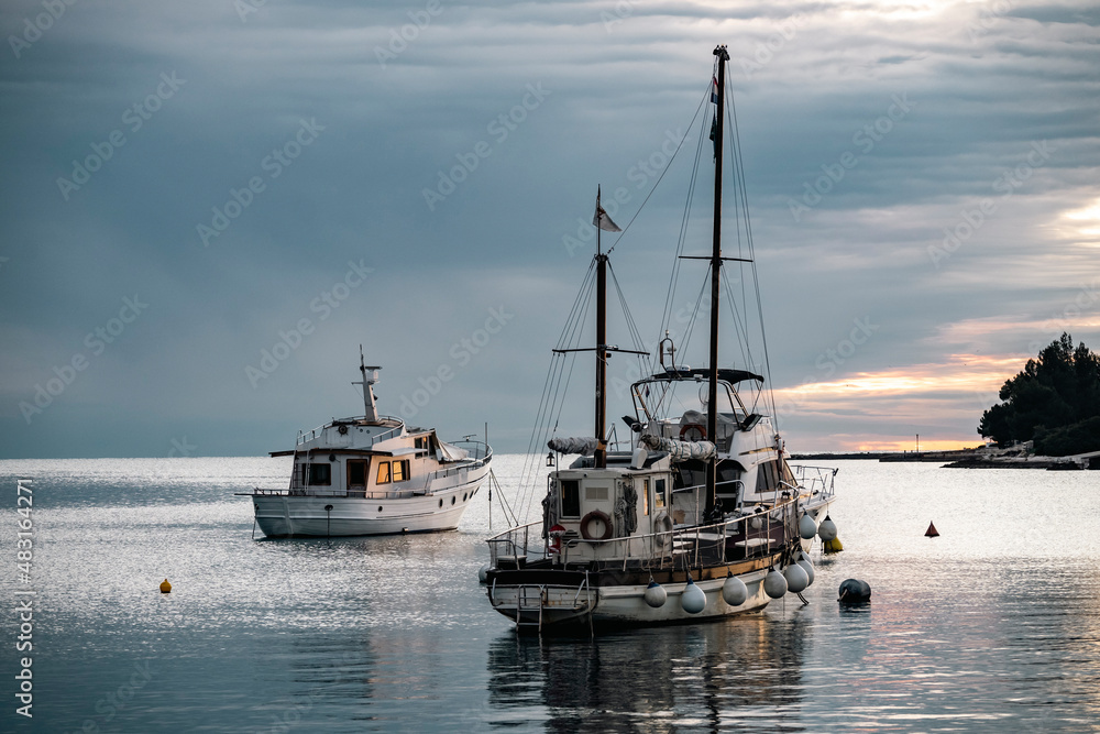 Beautiful winter sunset above calm, adriatic sea with anchored fishing boats before the nightfall in the Rovinj city port