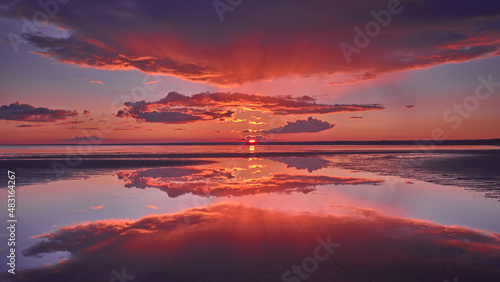 Fototapeta Naklejka Na Ścianę i Meble -  Sun rays and reflection of the sky in the water during a red sunset on the Gulf of Finland of the Baltic Sea.