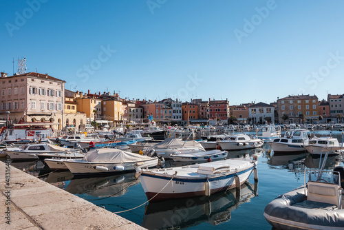 Fishing boats anchored in the Rovinj city port, Croatia, during crystal clear winter morning, lit by gentle sun