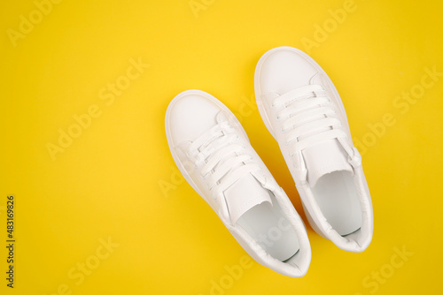 Casual comfortable white shoes.Stylish women's leather shoes with laces on a yellow background. Seasonal sales, promotions, discounts on shoes. Proper care for white skin.Top view.Copyspace