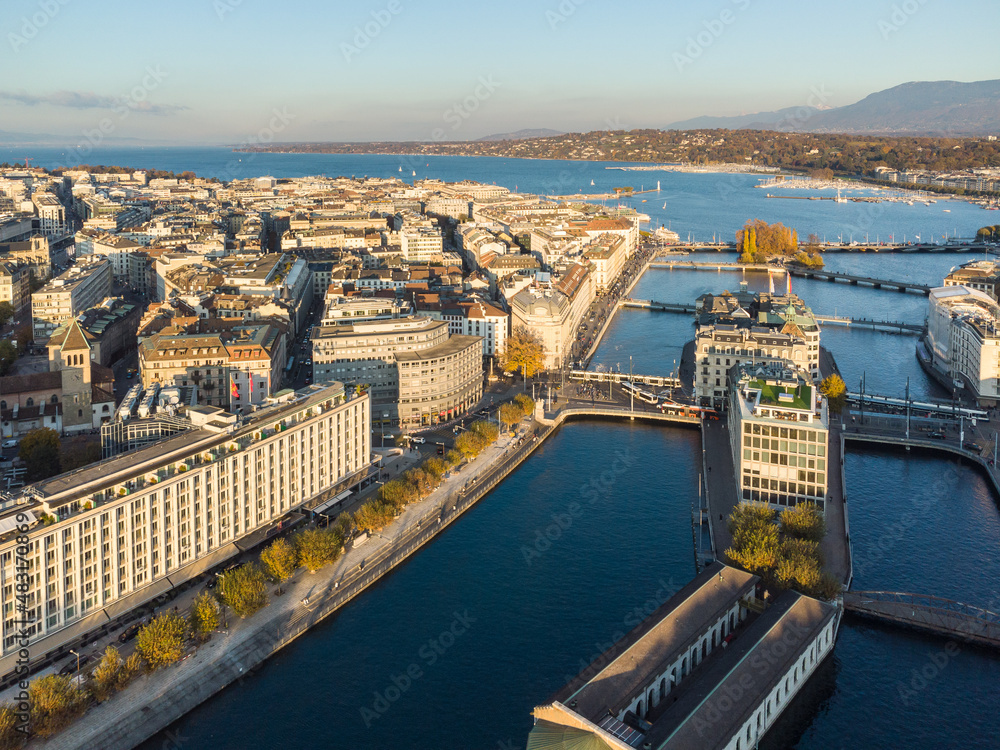 Obraz premium Aerial view of the Rhone river in the heart of Geneva old town and business district before reaching lake Geneva in Switzerland on a sunny fall day