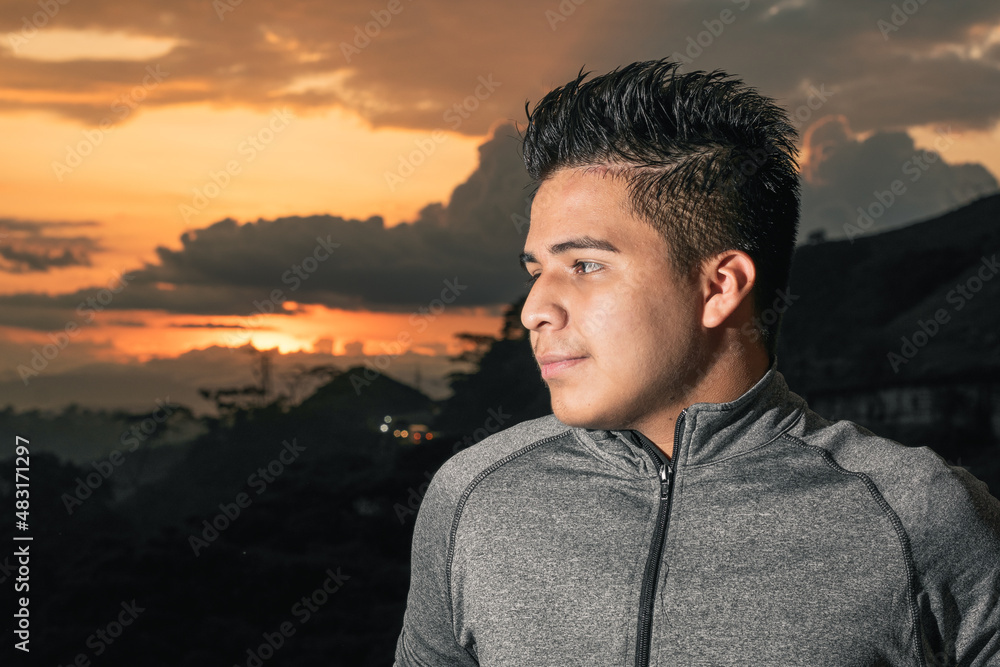 young brown-skinned latino with a beautiful sunset in the background, analyzing his future with a satisfied face, thinking about his life project. concept of education and tranquility. young brown-skinned latino with a beautiful sunset in the background, analyzing his future with a satisfied face, thinking about his life project. concept of education and tranquility.