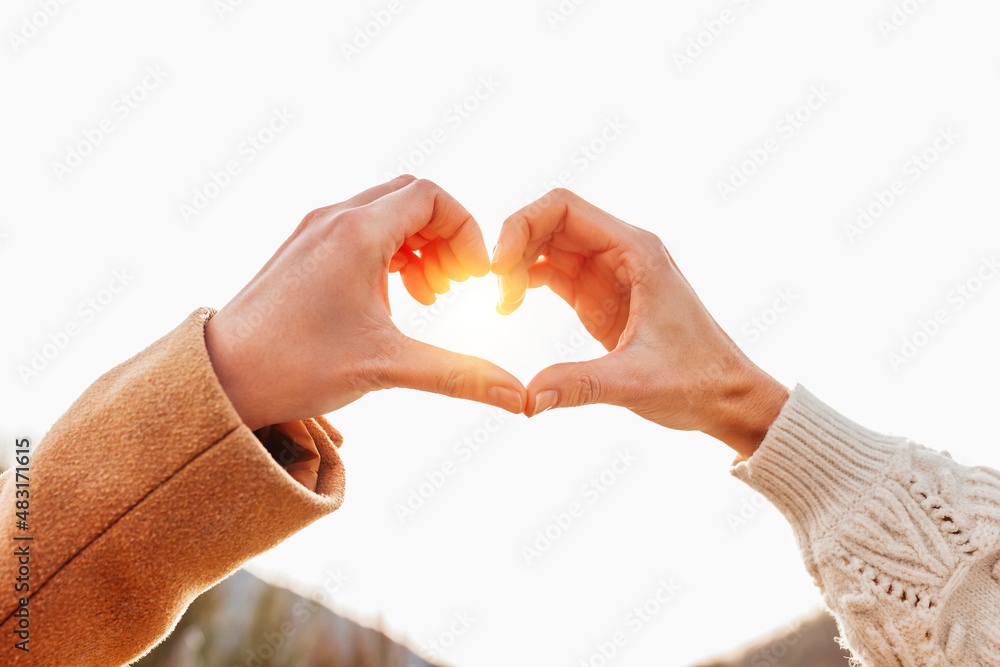 Close up of caucasian female hands in heart shape standing near mountain during winter holidays friendship. Lesbian homosexual couple. Peace and love concept. Close up of caucasian female hands in heart shape standing near mountain during winter holidays friendship. Lesbian homosexual couple. Peace and love concept.