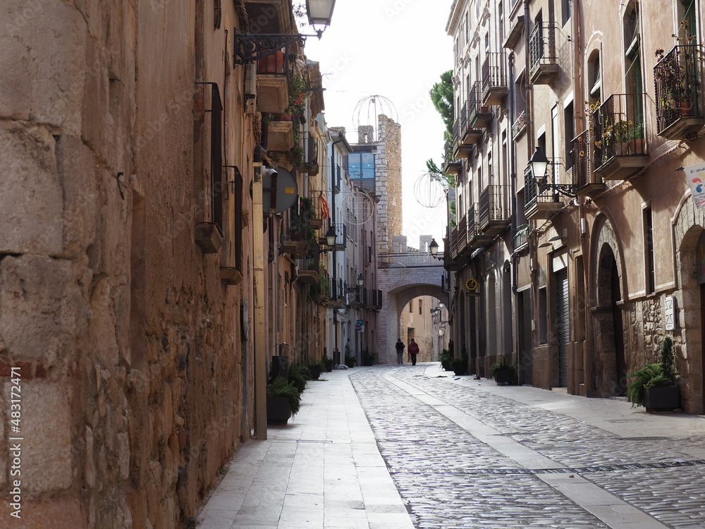 Fototapeta premium calle mayor dela villa medieval de montblanch con bonitos portales dovelados, al fondo uno de los arcos de entrada a la zona amurallada con su torre, tarragona, españa, europa