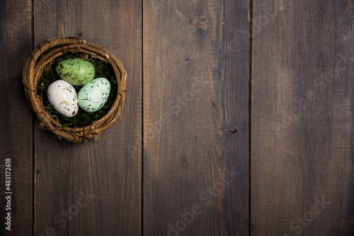 Three colorful easter eggs in a basket on a brown wood. High quality photo