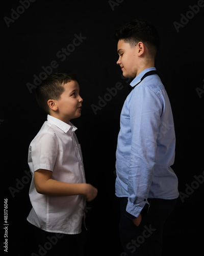 Two boys on a black background are brothers. they look at each other.Eye to eye