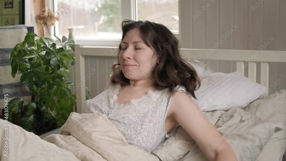 Happy positive middle age woman stretching in bed, wake up in good mood, welcoming new day. Smiling optimistic mature female awaken after healthy sleep in comfortable bedroom at home, Ordinary Morning Happy positive middle age woman stretching in bed, wake up in good mood, welcoming new day. Smiling optimistic mature female awaken after healthy sleep in comfortable bedroom at home, Ordinary Morning